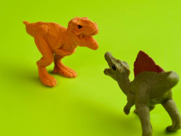 istock T-Rex and Spinosaurus figure fighting against green background 1311041024