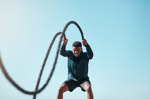 Cropped shot of a handsome young man using battle ropes during a high intensity workout outdoors