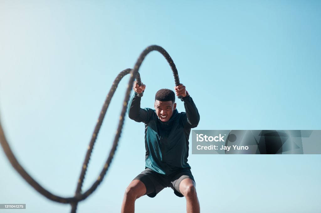 Muscles loading, please wait Cropped shot of a handsome young man using battle ropes during a high intensity workout outdoors Exercising Stock Photo