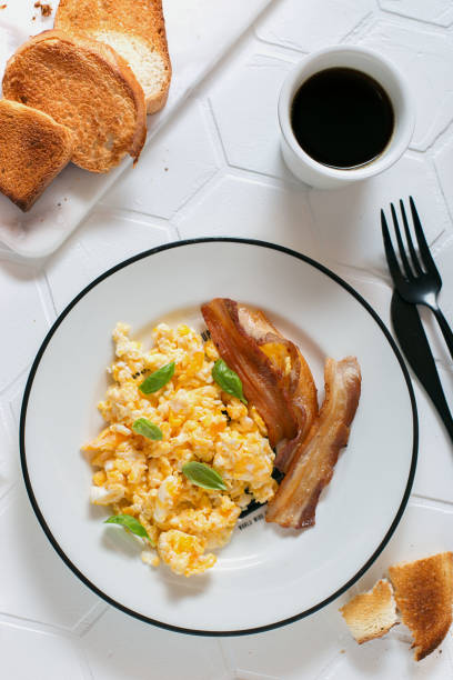 istock Breakfast for one person with scrambled eggs, bacon and coffee and toast, top view, selective focus 1311041283