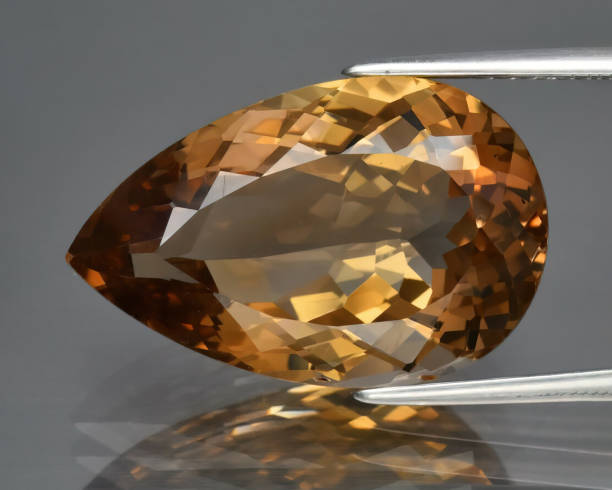 istock Natural gemstone orange imperial topaz on gray background 1311041306