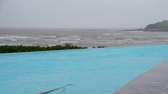 An infinity pool by the ocean on a wet and rainy grey overcast day