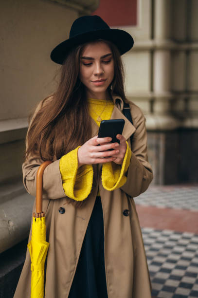 istock Woman with yellow umbrella using a smartphone 1311043299