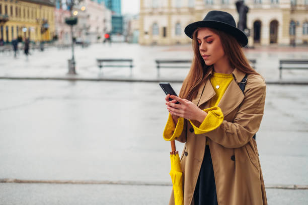 istock Woman with yellow umbrella using a smartphone 1311043302