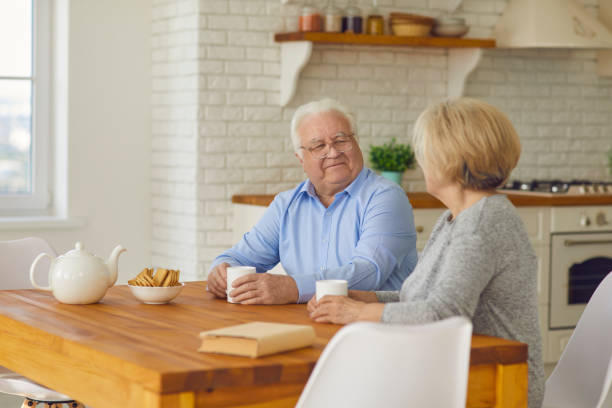 istock Happy senior couple sitting at kitchen table, drinking tea and enjoying quiet conversation 1311044618