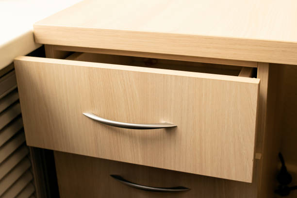 Hispanic young woman spraying and rubbing alcohol on office desk drawer to sanitize for COVID-19