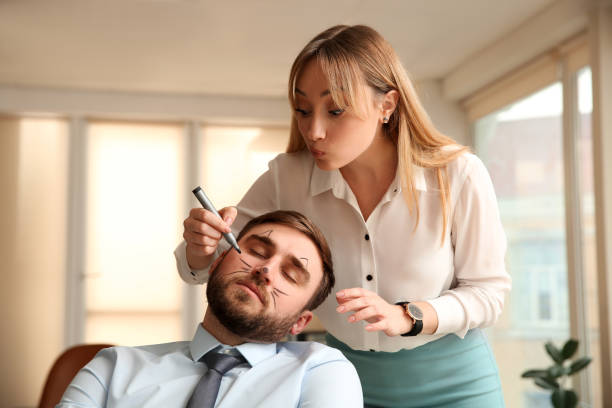 Young woman drawing on colleague's face while he sleeping in office. Funny joke