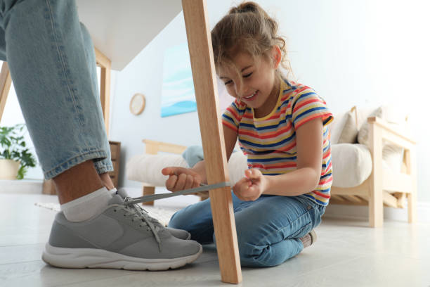Cute little girl tying shoe laces of her father together at home, closeup Cute little girl tying shoe laces of her father together at home, closeup fool photos stock pictures, royalty-free photos & images