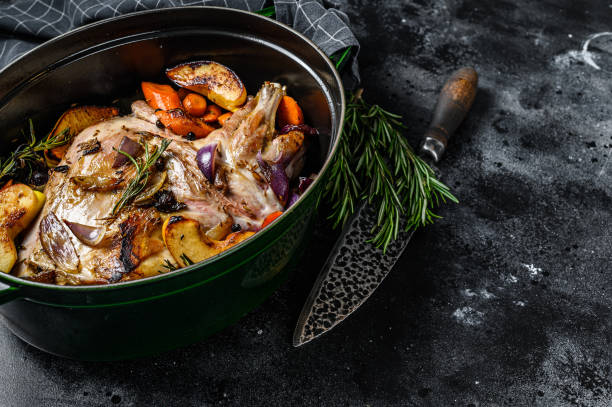 istock Baked whole lamb shoulder leg in a baking dish.  Black background. Top view. Copy space 1311047475
