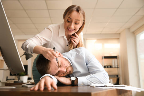 Young woman drawing on colleague's face while he sleeping in office. Funny joke Young woman drawing on colleague's face while he sleeping in office. Funny joke teasing photos stock pictures, royalty-free photos & images