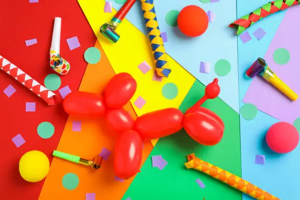 Clown's accessories and dog figure made of modelling balloon on color background