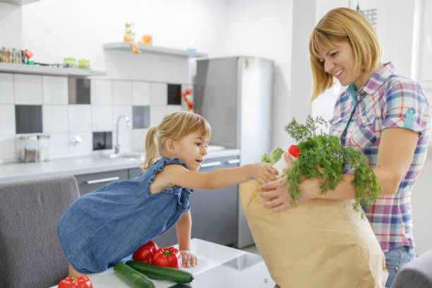 istock Child taking vegetables from grocery bag in her mother's hands 1311047934