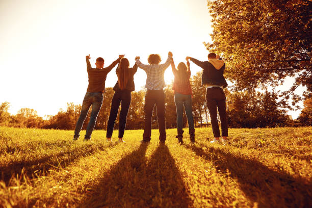 istock People standing with arms raised on meadow 1311048988