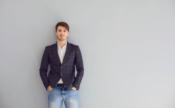 istock Young calm confident man in a casual jacket standing looking up over gray background. 1311050044