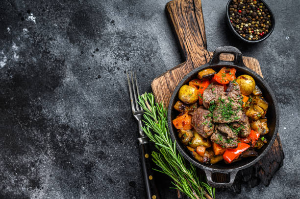 istock Meat stew in cooking pot on dark rustic cutting board. Black background. Top view. Copy space 1311050051