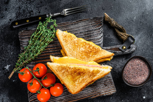 istock Grilled ham and cheese sandwich on a cutting board. Black background. Top view 1311053176