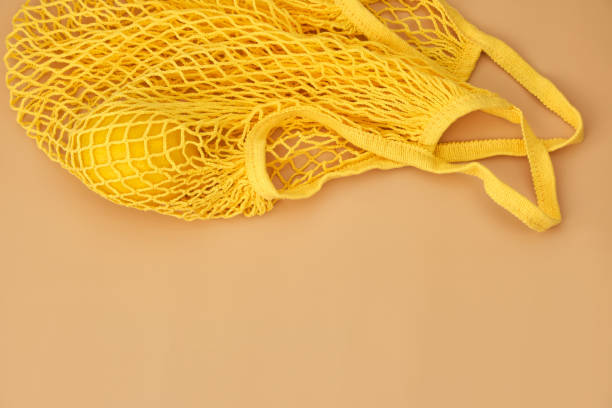 istock Mesh shopping bag with lemons on pink canvas background. 1311054722