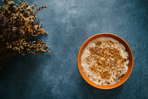 Rice pudding with cinnamon and almonds on blue background