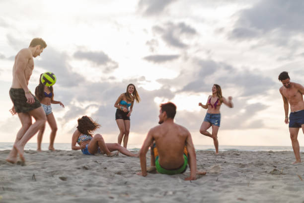 summer vacation with friends: out of pandemic beach party at sunset - beach volleying ball playing imagens e fotografias de stock