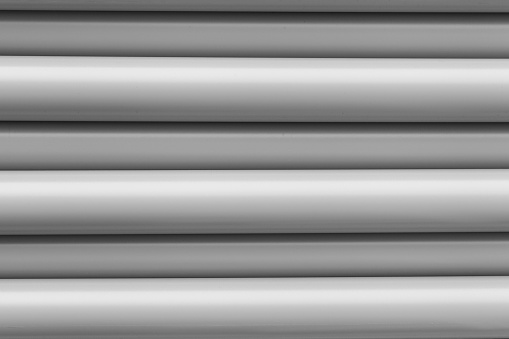 Stack of stored new grey PVC plastic pipes on the construction site