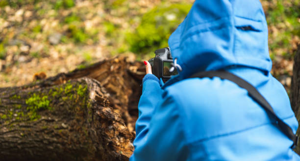 girl with blue jacket taking pictures with reflex camera in nature while raining.