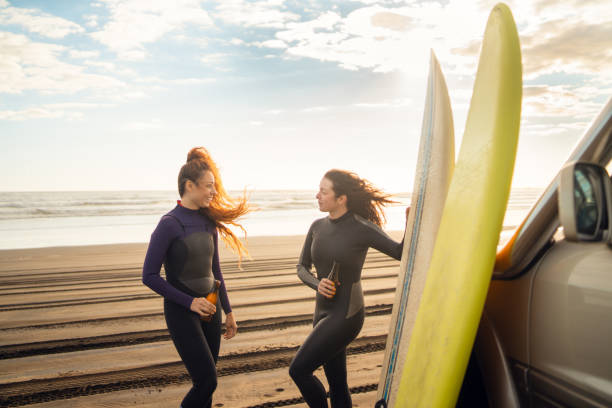 istock Surfers women having drinks with surfboard on the beach. 1311061500