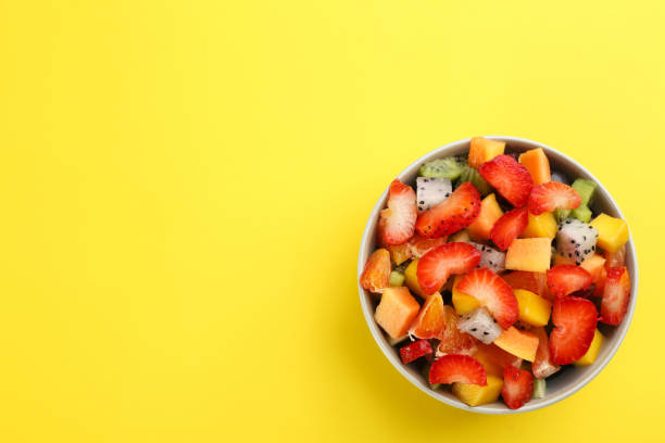 istock Delicious exotic fruit salad on yellow background, top view. Space for text 1311061660