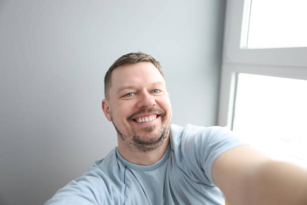 Young smiling man taking selfie at home