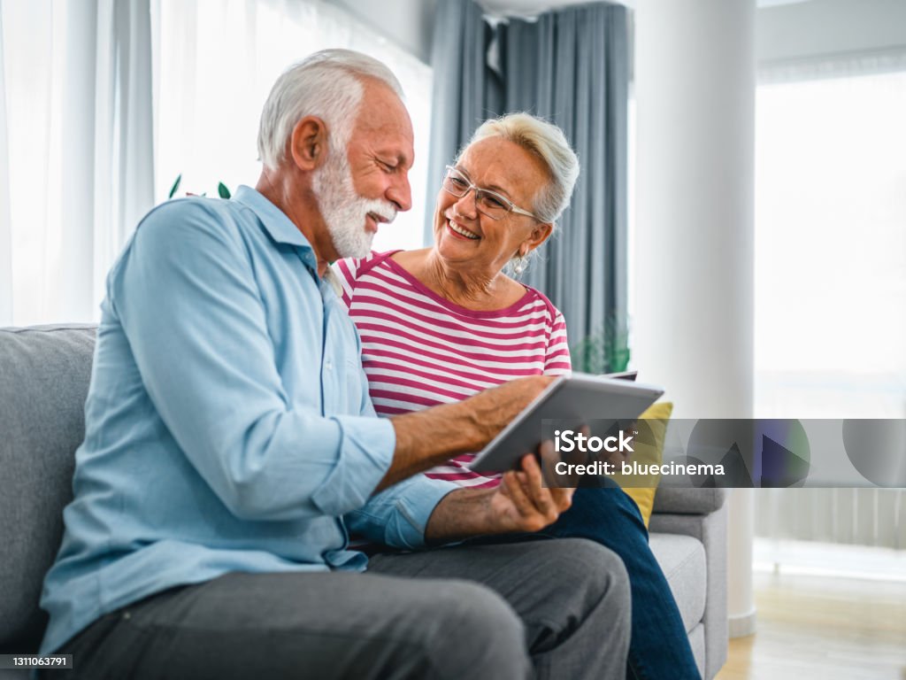 Senior couple buying some goods online Shot of a senior couple using a credit and digital tablet while working on their finances at home Digital Tablet Stock Photo