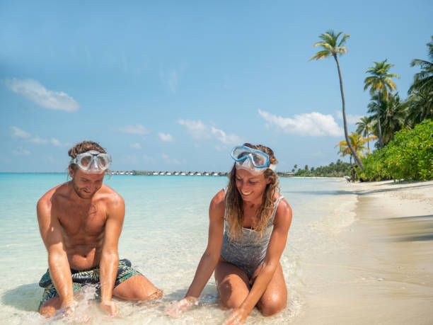 istock Young couple sitting in water playing together 1311063859