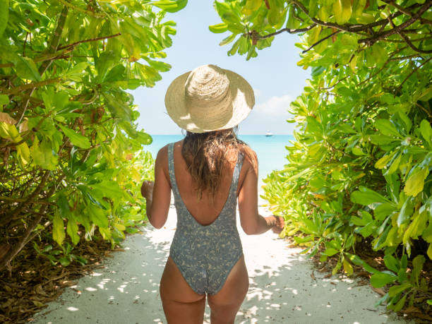 istock Young woman walks towards tropical beach 1311064101