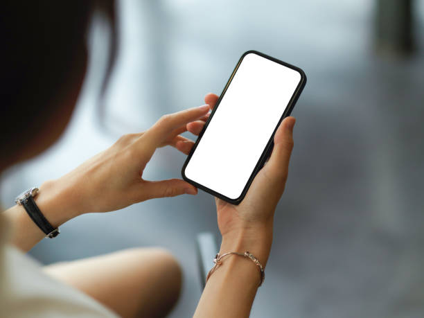 istock Over shoulder closeup view of female hands using mock-up smartphone screen 1311065617