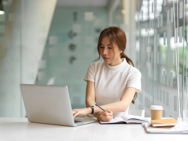 istock Female student doing assignment with laptop and paperwork in office room 1311065619