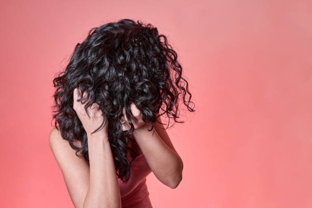 junge schwarz lockige behaarte frau kämmt ihre haare nach lockigen mädchen methode auf rosa hintergrund. haarpflegekonzept. - gelockt stock-fotos und bilder