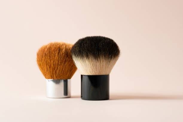 two kabuki brushes stand on a beige-pink background. - kabuki imagens e fotografias de stock