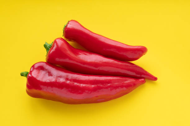 istock Three red sweet peppers lie on a yellow background 1311068618