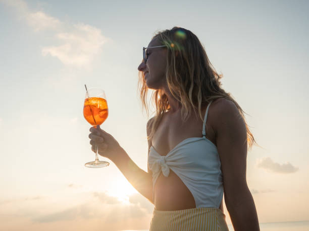 istock Woman drinking cocktail at sunset in an infinity pool 1311069598