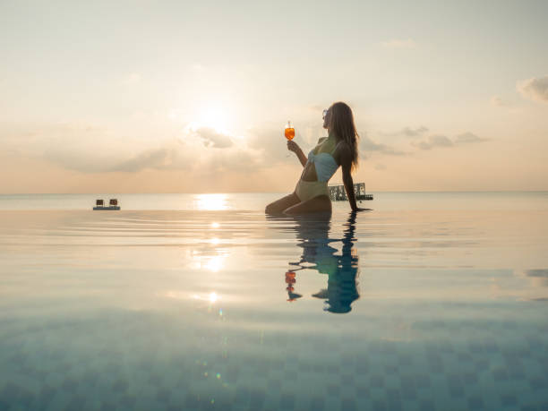istock Woman drinking cocktail at sunset in an infinity pool 1311069772