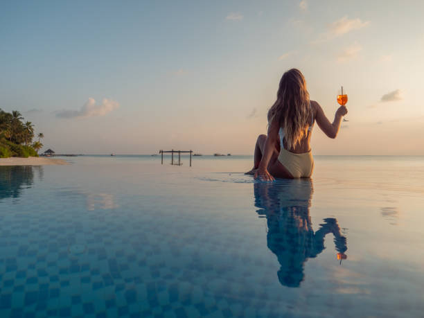 istock Woman drinking cocktail at sunset in an infinity pool 1311069868