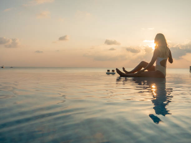 istock Woman drinking cocktail at sunset in an infinity pool 1311070078