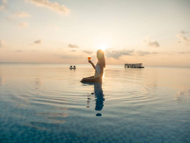 istock Woman drinking cocktail at sunset in an infinity pool 1311070080
