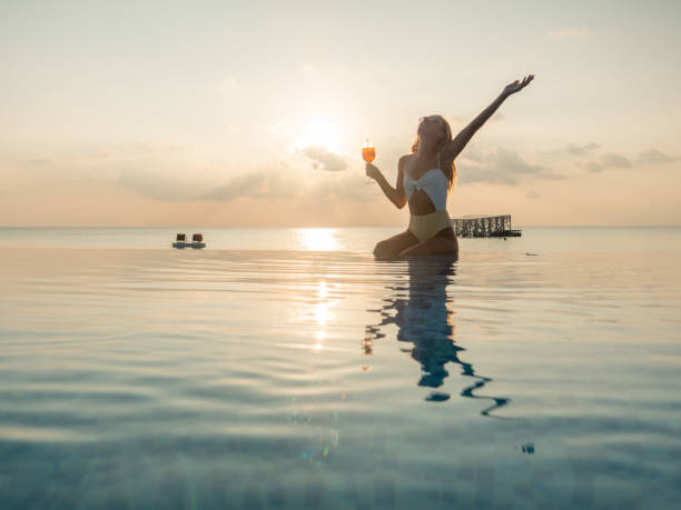 istock Woman drinking cocktail at sunset in an infinity pool 1311070164