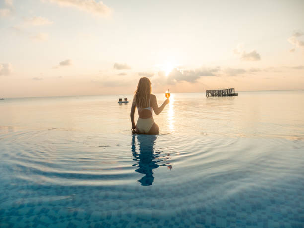 istock Woman drinking cocktail at sunset in an infinity pool 1311070244
