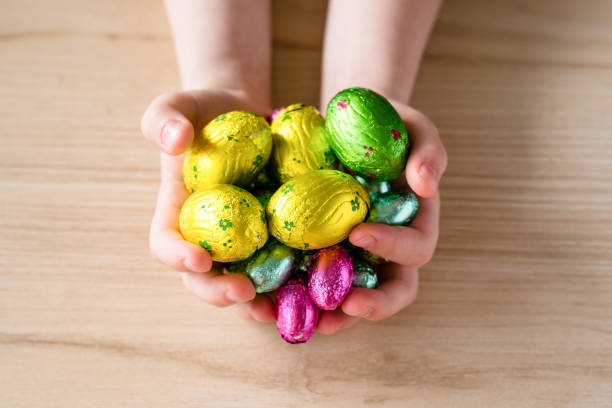 istock Easter candy eggs in children's hands. Wooden background, close-up 1311071208