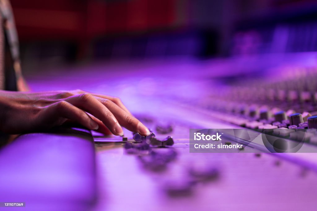 Woman's hand adjusting buttons on audio mixer Close-up of woman's hand adjusting buttons on audio mixer in recording studio. Sound Mixer Stock Photo