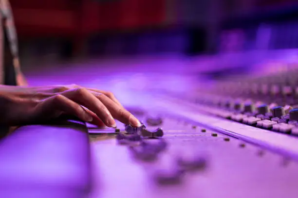Photo of Woman's hand adjusting buttons on audio mixer