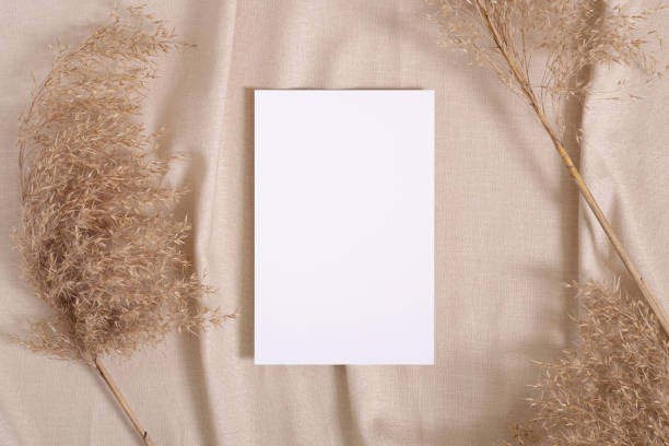 istock White blank paper card mockup with pampas dry grass on a beige neutral colored textile 1311074941