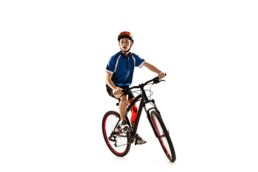 Race. Full -length portrait of young boy, bike rider on road bike isolated over white background. Bicyclist is training. Concept of sport, acton, motion, speed. Copy space for ad. Front view