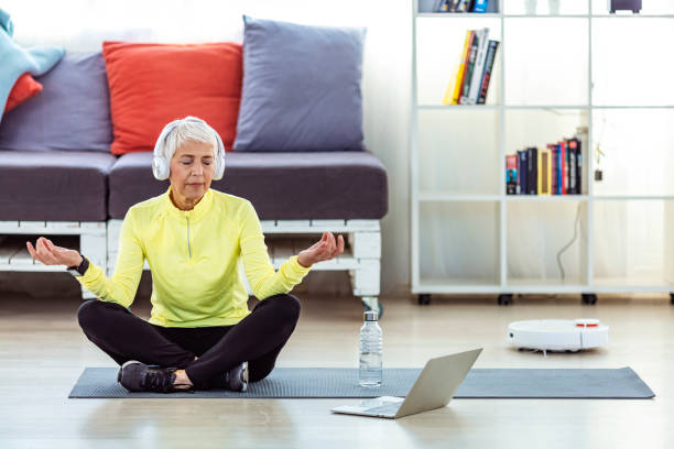 istock Senior Woman Meditating At Home While Using Robot Vacuum Cleaner 1311076278