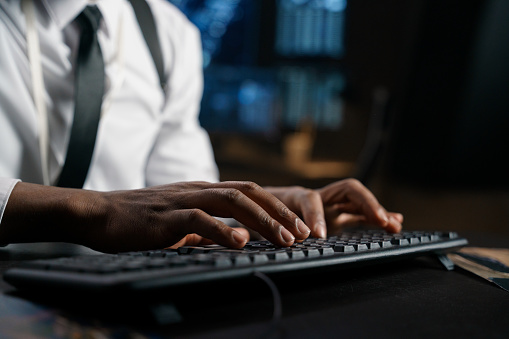 Close-up of the hands of a detective typing a report on the keyboard about the work done to his superiors. The cybercrime case is moving toward resolution.